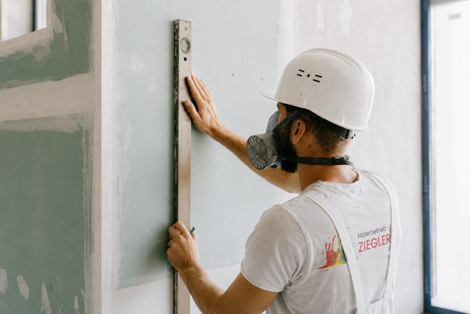 Maler des Malerbetriebs Ziegler prüft eine Wand mit der Wasserwaage