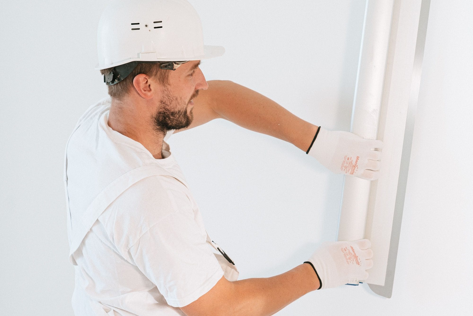 Maler des Malerbetriebs Ziegler bringt eine Leiste an einer weißen Wand an